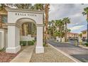 Community entrance featuring a white stone archway, well-manicured landscaping, and mature palm trees at 251 S Green Valley Pkwy # 1311, Henderson, NV 89012