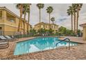 Relaxing community pool surrounded by palm trees and lounge chairs on a brick patio at 251 S Green Valley Pkwy # 1311, Henderson, NV 89012