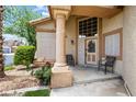 Inviting front porch with decorative glass door, accent chairs and manicured landscaping at 5449 Desert Spring Rd, Las Vegas, NV 89149