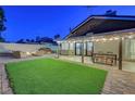 Serene backyard featuring artificial turf, a seating area with fire pit, and covered patio for outdoor dining at 58 Pleasant Dale Dr, Henderson, NV 89074