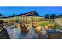 Inviting outdoor patio with wicker furniture, stylish pavers, a modern fire pit, and ambient string lights at 58 Pleasant Dale Dr, Henderson, NV 89074