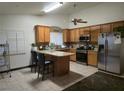 Bright kitchen featuring wood cabinets, stainless steel appliances, island with seating, and tile flooring at 6361 Copperfield Ave, Las Vegas, NV 89108