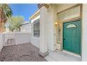 Charming home entrance featuring a decorative green door, classic sconce and freshly manicured landscaping at 6844 Tropicaire St, Las Vegas, NV 89149