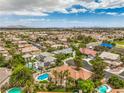 Expansive aerial view capturing the residential neighborhood, pools, landscaping, and the distant cityscape and mountains at 7730 Brambly Creek Ct, Las Vegas, NV 89129
