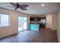 Open-concept living space with wood floors, ceiling fan, and a view of the modern kitchen and private backyard at 2761 Frosted Teal Ave, North Las Vegas, NV 89086