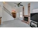 Open living room with a brick fireplace, a staircase with black railing, and a view of the front door at 6436 Deadwood Rd, Las Vegas, NV 89108