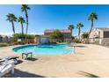 Community pool with tall palm trees and lounge chairs, set against a backdrop of residential houses at 6549 Clara Bow Ave # 103, Las Vegas, NV 89122