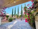 Landscaped backyard featuring a fountain, brick-paved patio, mature trees, and vibrant bougainvillea at 7083 Seat Wall Rd, Las Vegas, NV 89148