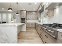 Bright kitchen features an island with a marble countertop, wood-colored cabinets, and stainless steel appliances at 8095 Carpenter Creek Ave, Las Vegas, NV 89113