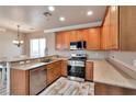 Well-lit kitchen features stainless steel appliances, wood cabinets, granite countertops, and wood-look tile floors at 8152 Satin Carnation Ln, Las Vegas, NV 89166