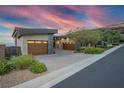 Contemporary home featuring multi-car garage, desert landscaping, and stone accents against a vibrant twilight sky at 1228 Stellar Rim Ct, Henderson, NV 89012