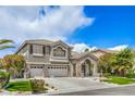 Two-story home with a combination of gray stucco and stone accents, three-car garage, and manicured lawn at 2959 Azure Bay St, Las Vegas, NV 89117