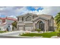 Two-story home with stone and gray stucco featuring a three-car garage, and landscaped front yard at 2959 Azure Bay St, Las Vegas, NV 89117