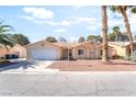 Inviting single-story home, featuring desert landscaping, two-car garage, and palm trees, under a sunny sky at 3145 Tarpon Dr, Las Vegas, NV 89120
