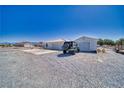 Exterior view features a house with an attached garage and additional separate garage with a desert landscape at 3581 Margarita Ave, Pahrump, NV 89048