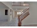 Bright, two-story foyer featuring tile flooring, a staircase with carpeted treads and dark wood railing at 5912 Kit Cove Ct, Las Vegas, NV 89131
