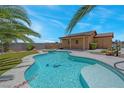 Sparkling in-ground pool and spa surrounded by green turf, desert landscaping, and a covered patio at 7668 Friendly Breeze Ct, Las Vegas, NV 89123