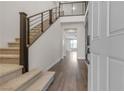 Bright entryway featuring wood floors, carpeted stairs, a modern railing, and an open floor plan at 9917 Fletcher Peak Ave, Las Vegas, NV 89178