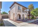 Two-story stucco home with a tile roof, arched entryway, balcony and manicured landscaping at 10345 Howling Coyote Ave, Las Vegas, NV 89135