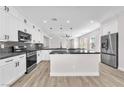 Modern kitchen featuring white cabinets, dark countertops, stainless appliances and wood-look floors at 10345 Howling Coyote Ave, Las Vegas, NV 89135