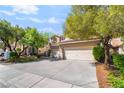Charming two-story home with a red tile roof, a spacious driveway, and mature trees at 1553 Ravanusa Dr, Henderson, NV 89052