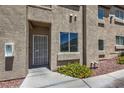 Close-up of a condo entrance with a security door, window, and landscaped flower bed at 2110 Los Feliz St # 1003, Las Vegas, NV 89156
