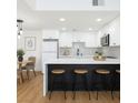 Stylish kitchen with white cabinets, a dark island with seating, and modern lighting fixtures at 3770 Shirebrook Dr # 160, Las Vegas, NV 89115