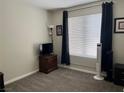 A carpeted bedroom with simple furnishings and a neutral color scheme and a large window at 7812 Sedalia St, Las Vegas, NV 89139