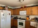 A compact kitchen with wooden cabinets, white appliances, and granite-look countertops at 7812 Sedalia St, Las Vegas, NV 89139