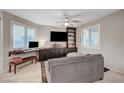 Cozy living room featuring large windows with plantation shutters, gray sofa, and entertainment center at 9327 S Chieftain St, Las Vegas, NV 89178
