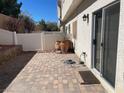 Private backyard with a brick paver patio, decorative pots, and a white fence creating a cozy outdoor space at 9333 Leaping Deer Pl # 103, Las Vegas, NV 89178