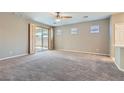 Spacious living room with a ceiling fan, neutral walls, carpet flooring, and sliding door access to the patio at 10667 Casa Bianca St, Las Vegas, NV 89141
