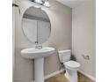 Powder room with pedestal sink, toilet, round mirror, and neutral wall paint at 11014 Great Sioux Rd, Las Vegas, NV 89179