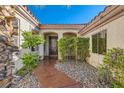 Charming home entrance with stone walkway, mature landscaping, and wrought iron security gate at 151 Cliff Valley Dr, Las Vegas, NV 89148