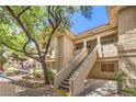 Exterior view of a building showing stairs to upper units, mature trees, and ample parking at 1557 Lake Placid Ter # 1557, Henderson, NV 89014