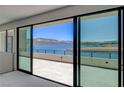 Large sliding glass doors open to a balcony and a stunning view of the lake and mountains at 1600 Pleasant Bay Ct, Henderson, NV 89011