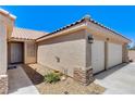 Close-up of home's entrance and garage, featuring stone accents and tidy landscaping at 2848 Skowhegan Dr, Henderson, NV 89074