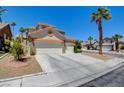 Inviting home exterior featuring a spacious driveway, a three-car garage, and desert landscaping at 4835 Willow Glen Dr, Las Vegas, NV 89147