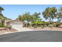 View of the charming home with a desert landscape, mature trees, and a two-car garage at 5529 Cranwood Ct, Las Vegas, NV 89130