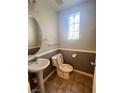 Half bathroom with a pedestal sink, toilet, and decorative window, offering style and functionality at 6545 Netherseal Ave, Las Vegas, NV 89139