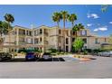 Well-maintained condo building with covered parking, manicured landscaping, and tall palm trees on a clear sunny day at 7173 S Durango Dr # 307, Las Vegas, NV 89113