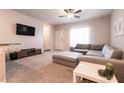 Bright living room featuring carpet, a gray sectional, ceiling fan, and a wall-mounted television at 7302 Sunray Point St, North Las Vegas, NV 89084