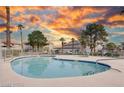 Community pool with a clean white fence, blue water, and desert landscaping with a vibrant sunset at 1300 Pinto Rock Ln # 201, Las Vegas, NV 89128