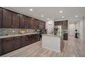 Well-lit kitchen featuring dark wood cabinets, stainless steel appliances, an island with seating, and stylish countertops at 205 Piedmont Alps St, Henderson, NV 89012