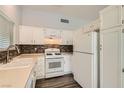 Bright kitchen features white cabinets, stainless steel sink, modern laminate floor, and mosaic backsplash at 318 Heather Dr, Henderson, NV 89002
