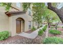 Inviting entrance with an arched doorway, brown door, and manicured shrubs along a walkway at 3930 Legend Hills St # 102, Las Vegas, NV 89129