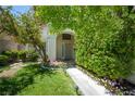 Inviting front yard with lush greenery, flowers, and a well-manicured lawn leading to the entrance at 4521 Crimson Leaf Dr, Las Vegas, NV 89130