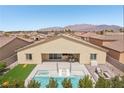 An aerial view of a backyard featuring a pool and spa, a patio, artificial grass, and mountain views in the distance at 5321 Brayden Ct, Las Vegas, NV 89131