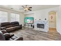 Cozy living room with a stone fireplace, large windows, neutral walls, and wood-look floors at 564 Lampshire Ln, Pahrump, NV 89060