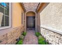 Inviting entryway with a stone-paved walkway and a double-door entrance, flanked by lush greenery and sconces at 6567 American Eagle Ave, Las Vegas, NV 89131